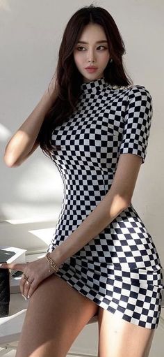Woman in a black and white checkered dress posing indoors