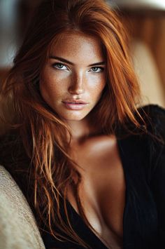 Woman with red hair and freckles in a black top with deep cleavage