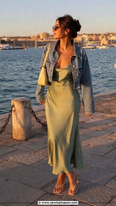 Woman in a denim jacket and slip dress by the waterfront at golden hour