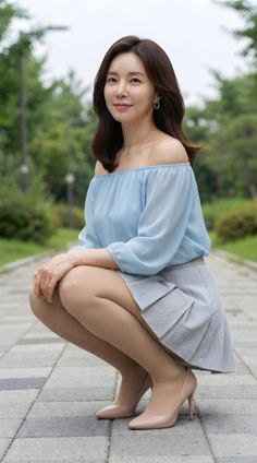 Woman in an off-shoulder top and mini skirt squatting outdoors