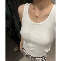 Woman in a white tank top and striped pants with a gold necklace