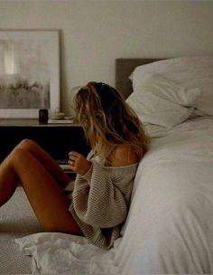 Woman with long hair wearing an oversized sweater in a bedroom