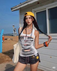Woman with braided hair and a yellow cap wearing a ripped tank top at the beach