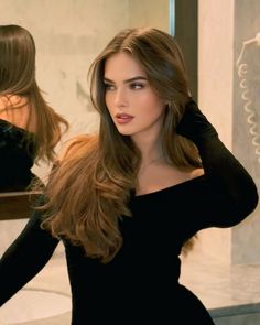 Woman with long brown hair in an off-shoulder top looking to the side