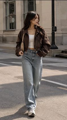 Woman in a brown jacket and wide leg jeans walking on a street