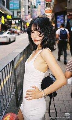 Woman with short black hair in a white tank top on a city street