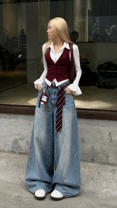 Woman with long blonde hair wearing a maroon vest and wide leg jeans outdoors