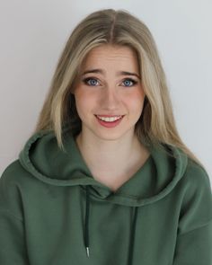 Young woman with blonde hair and blue eyes wearing a green hoodie