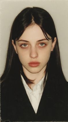 Young woman with long black hair wearing a white shirt and black jacket