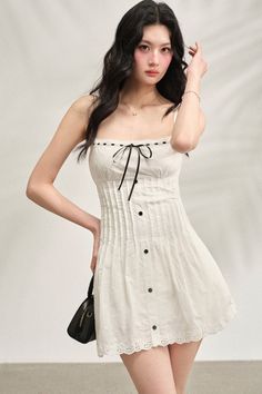 Woman in a white dress with a black ribbon and black handbag