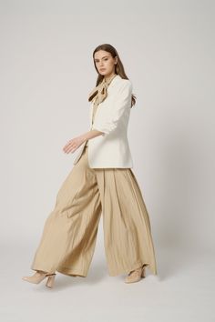 Woman in a white blazer and wide leg pants with a bow necktie
