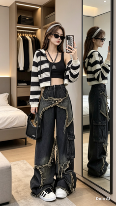 Woman in a striped hoodie, crop top, and ripped jeans posing indoors