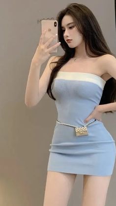 Woman in a light blue strapless mini dress taking a mirror selfie