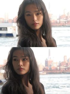 Woman with long dark hair by a waterfront with a cityscape in the background