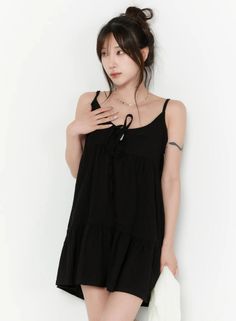 Woman in a black dress with hair in a bun against a white background
