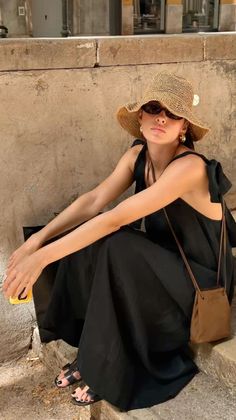 Woman in a black dress and straw hat sitting outdoors