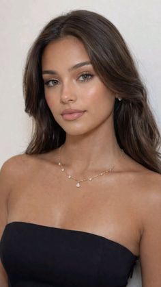 Woman with long brown hair wearing a black strapless top and a delicate necklace
