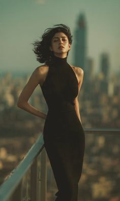 Woman in a black dress on a rooftop with a cityscape background