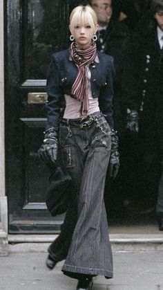 Person with blonde hair and a striped scarf wearing a cropped jacket and pinstripe pants