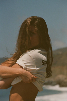 Woman pulling up her t-shirt on a sunny beach