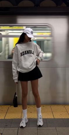 Person in a white sweatshirt and black mini skirt at a subway station