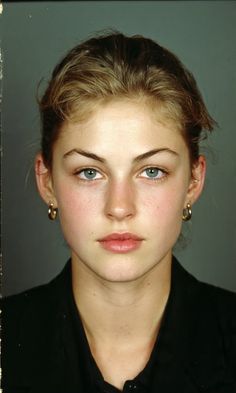 Woman with blonde hair and blue eyes wearing a black shirt and hoop earrings