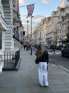 Woman with long hair walking on a city street with a Union Jack flag overhead