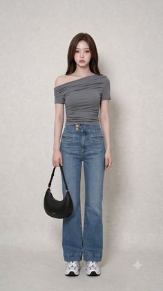 Woman in an off-shoulder top and blue jeans holding a black handbag
