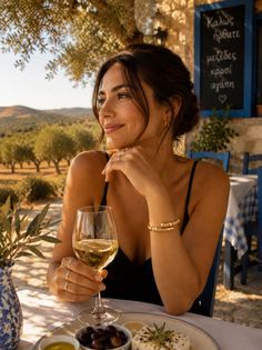 Woman in a black dress enjoying wine and appetizers at an outdoor restaurant