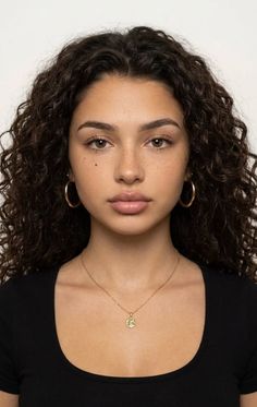Woman with curly hair and freckles wearing a black shirt and gold jewelry