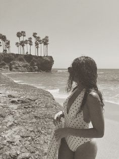 Woman in a polka dot swimsuit on a beach with palm trees in monochrome