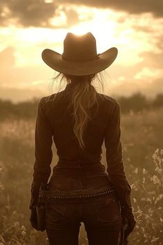 Woman in a cowboy hat facing away into a golden hour sunset