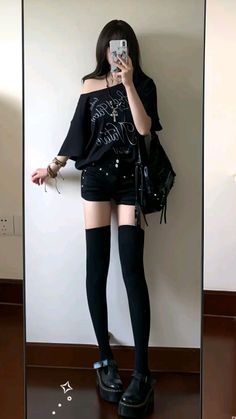 Person in black outfit taking a mirror selfie indoors