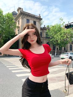 Woman in a red crop top and black pants on a city street