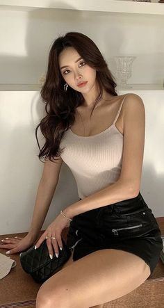Woman with long hair wearing a tank top and black shorts indoors