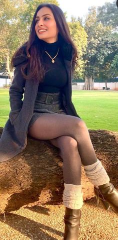 Woman with long hair wearing a black turtleneck and mini skirt sitting outdoors