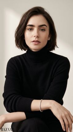 Woman with short dark hair wearing a black turtleneck and diamond bracelet