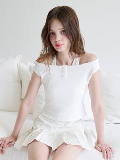 Young woman with long hair wearing a white top and pleated skirt indoors