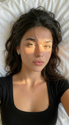 Woman with dark hair and freckles, illuminated by soft lighting