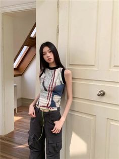 Woman with long black hair wearing a sleeveless top and cargo pants indoors
