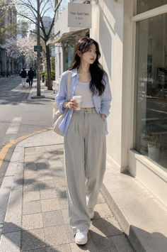 Woman in a light blue shirt and wide leg pants walking on a city street