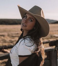 Woman in a cowboy hat and t-shirt outdoors during golden hour
