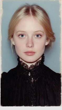 Blonde woman with blue eyes wearing a black dress with a lace collar
