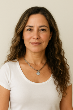 Woman with long wavy hair wearing a white t-shirt and silver necklace