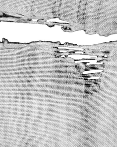 Close up of torn white fabric with visible threads and holes