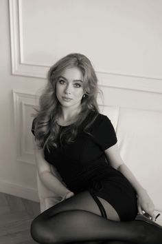 Woman in a black dress and stockings posing on a couch in black and white