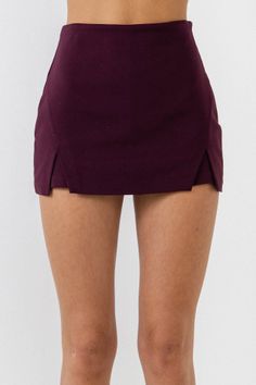 Lower body of a person wearing a burgundy mini skirt against a white background