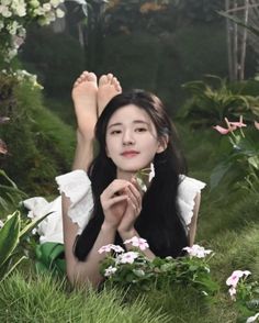 Woman with long dark hair lying on grass, holding a white flower