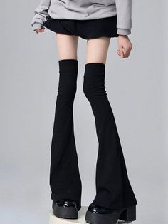 Person in a gray hoodie, black skirt, and platform shoes with exposed thighs