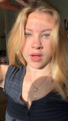 Young woman with blonde hair and blue eyes wearing a heart necklace